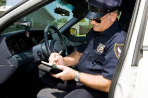Police officer in his squad car, filling out a citation.